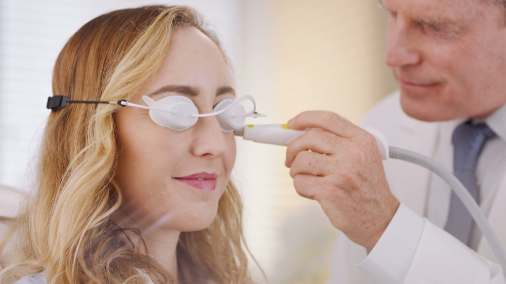 A provider treating the skin under a patient's eyes with the Optilight IPL handpiece while her eyes are covered by protective shields
